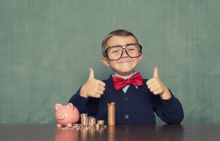 Petit garçon pouces en l'air devant un tas de pièces