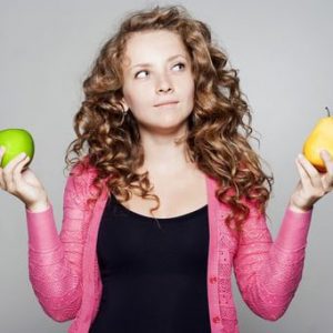 Jeune femme tenant pomme et poire dans chaque main