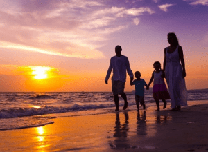 Famille se promenant sur la plage - coucher de soleil