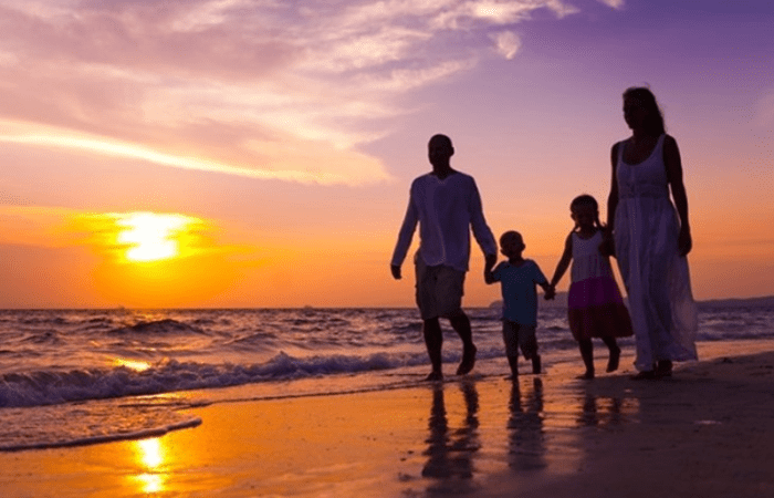 Famille se promenant sur la plage - coucher de soleil